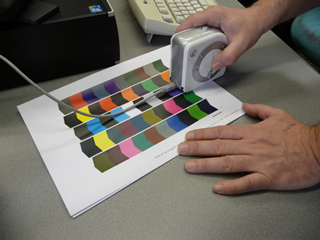 Midiendo los parches de tinta de una impresora con un espectrofotómetro para caracterizarla.